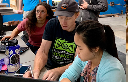 Nicholas Galitzki (seated at center) runs the data with students at the High Bay lab